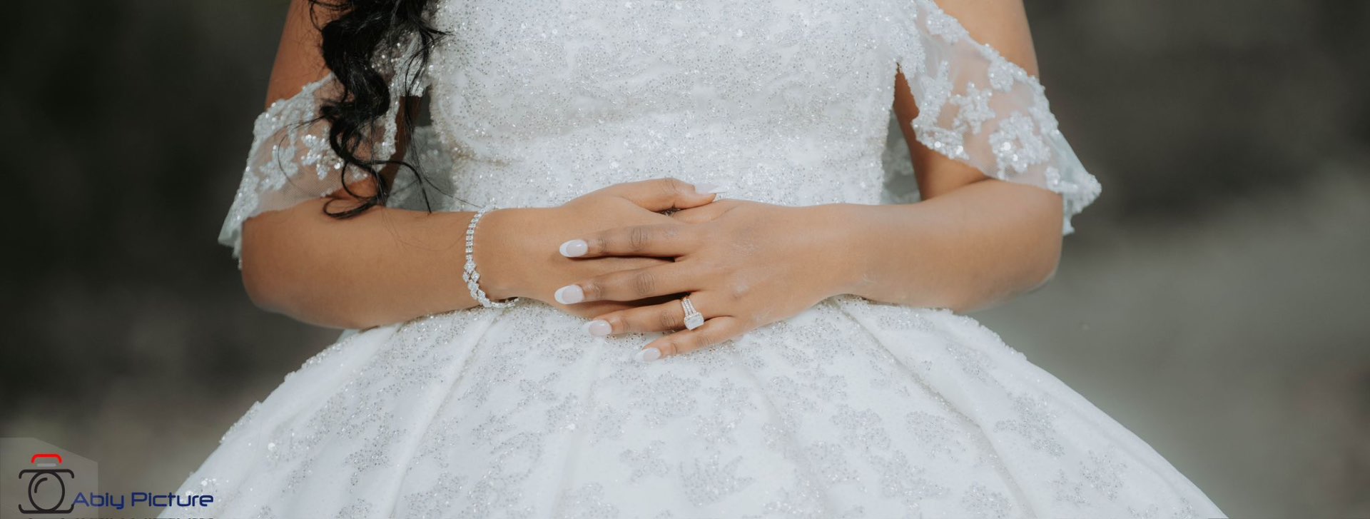 Close detail of a beaded bridal gown and engagement ring