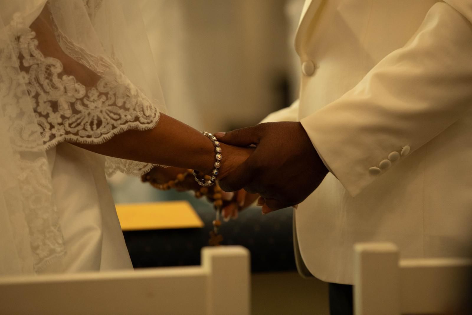 Bride and groom holding hands with a rosary during the church ceremony
